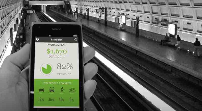 A person in the DC metro holding a phone with Sitegeist app showing average rent nearby